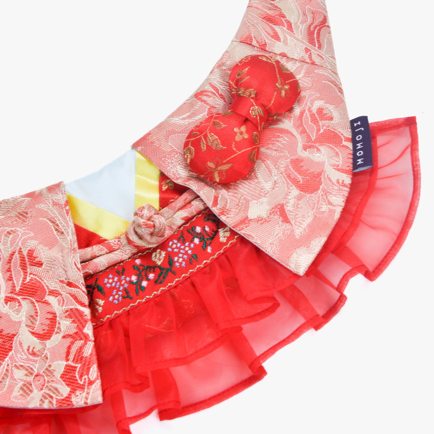 Close-up of the Shine bandana's floral brocade, heart button and red tulle