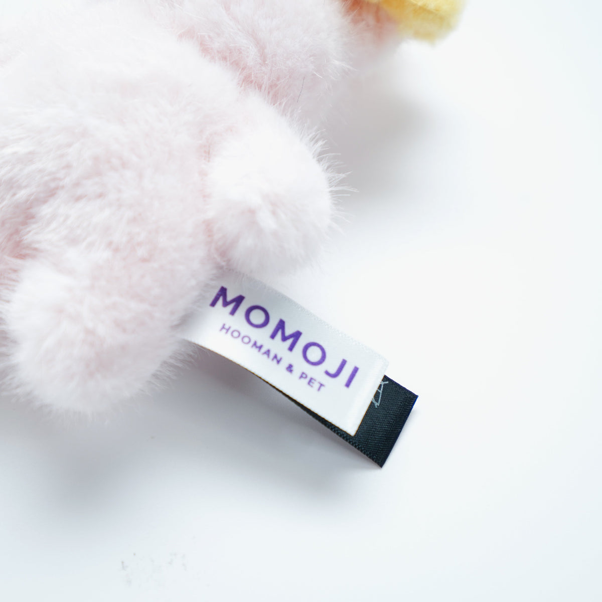 Close-up of the pink Momoji Bear plush and its label