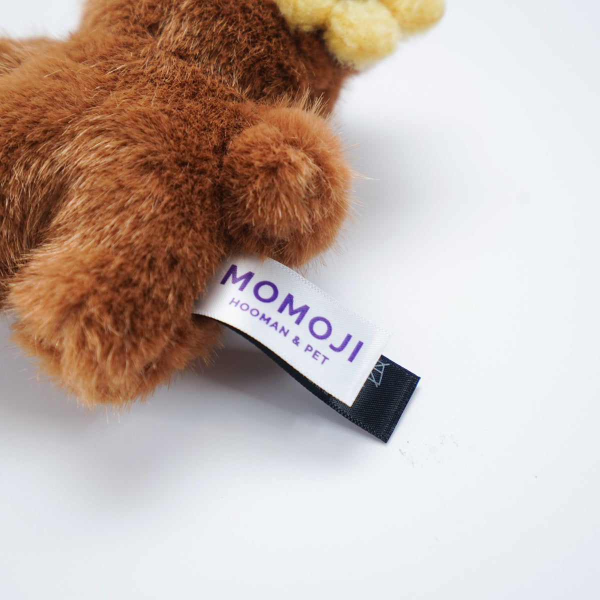 Close-up of the brown Momoji Bear plush and its label
