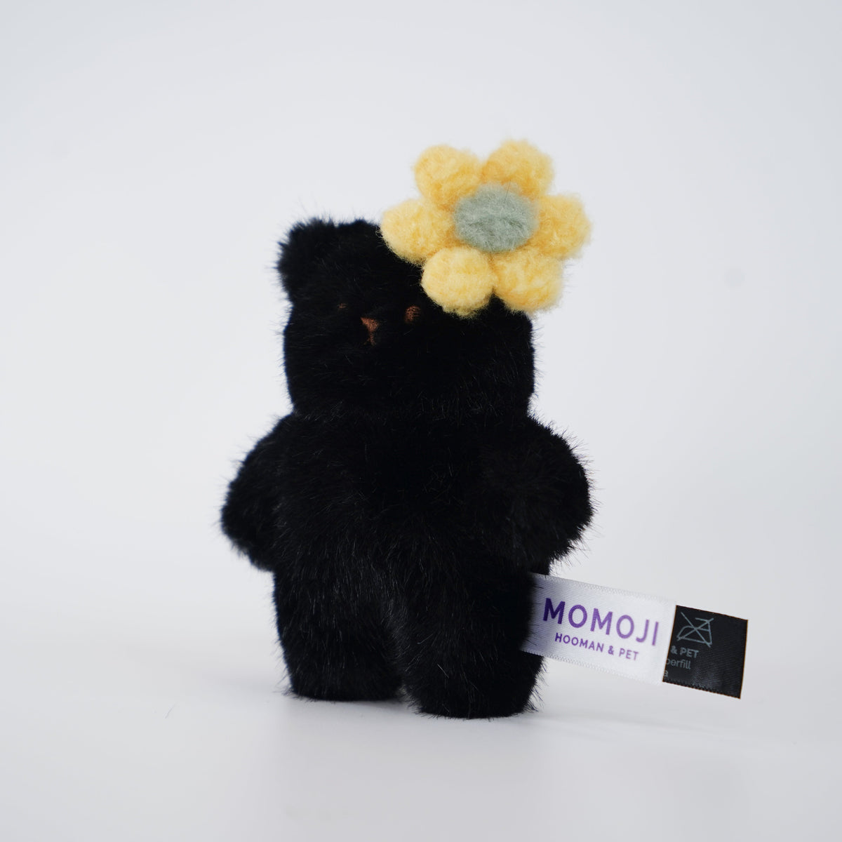 Small black Momoji Bear plush with yellow flower clip