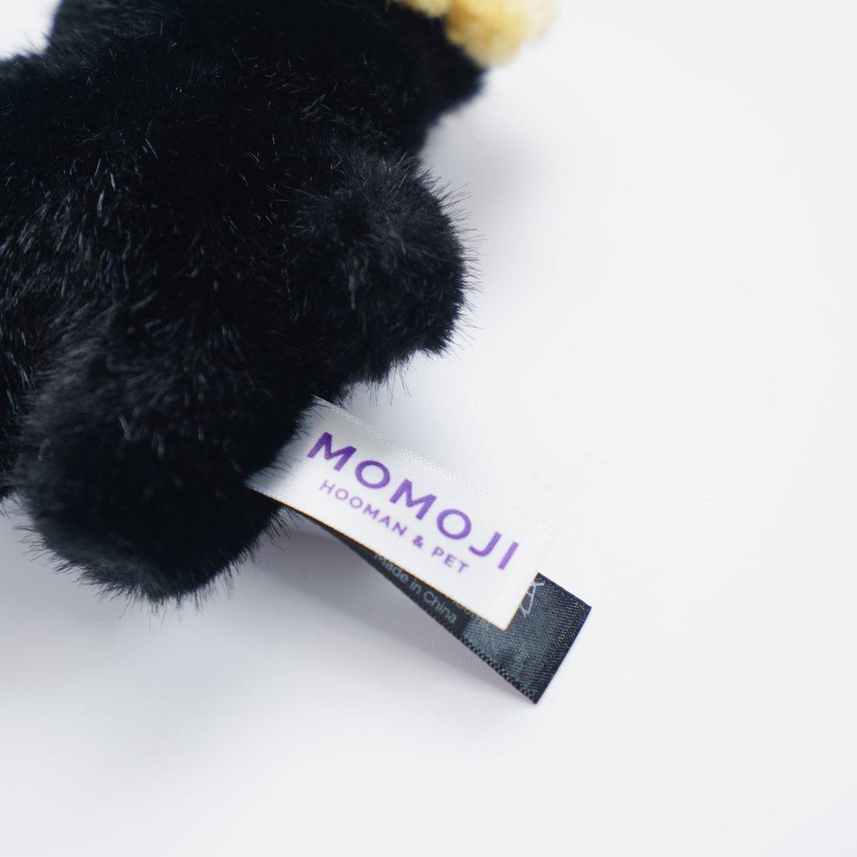 Close-up of the black Momoji Bear plush and its label