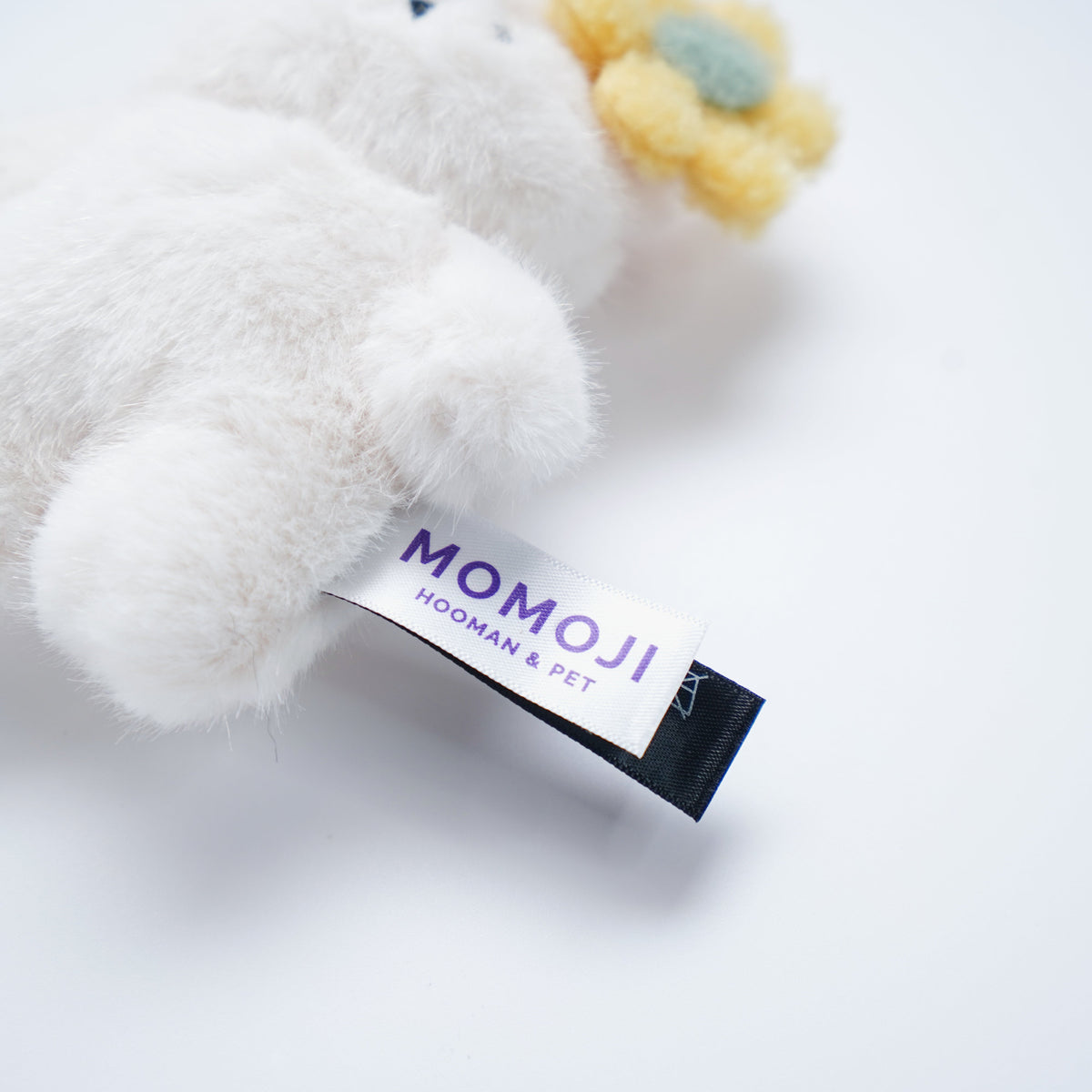 Close-up of the white Momoji Bear plush and its label